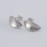 A pair of 14K white gold stud earrings with a single central diamond, set in a brushed matte finish.